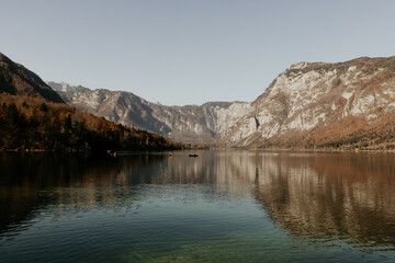 Fototapeta premium A stunning landscape at lake Bohinj in Slovenia. Beautiful mountain and cristal clear water. Reflection on water. Daylight and soft lights. Boat on the image. Autumn in the Alps. Place to visit. 