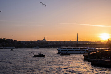 Outstanding yellow sunset of the Turkish sea, flying seagulls and boats swimming across