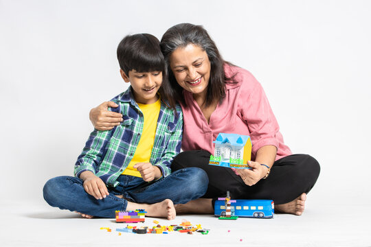 Happy indian grandmother and grandson playing with colorful Toys, Isolated on white studio background, Grandma Teaching Male Grandchild, Learning Concept.