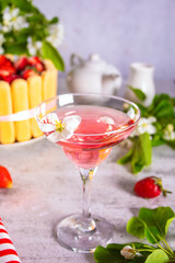 Glass of pink cocktail, cake with fresh strawberries with flowers branch of apple tree. Wedding or Valentines day romatic date couple concept.