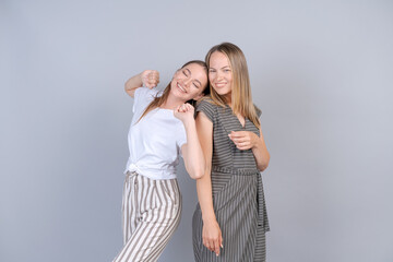 Mother and daughter are hugging and having fun together on background in studio in light casual clothes in pastel colors. Portrait happy women smiling with happiness and joy. Concept unity in family