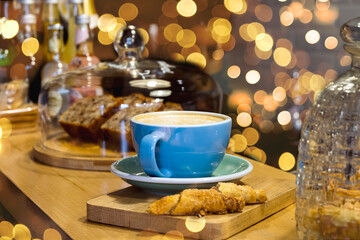 Tasty plain cup of latte on a wooden table in a coffee shop, bokeh lights on the background