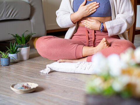 Woman meditating at home and breathing with hands on chest for mantra and balance. Deep breath in meditation for balance and calm anxiety. Mental health exercise. Alternative therapy © OlgaPS