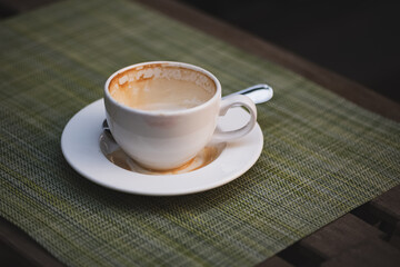 Empty coffee cup with stamps of milk froth and light lipstick imprint on the edges on table of outdoor cafe