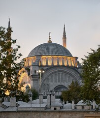 Fototapeta na wymiar Istanbul cityscape - panoramic view of Suleymaniye Mosque in the evening with light. Traditional arabic town with silhouettes of minarets on sunset, ancient landmarks of muslim architecture in Turkey.