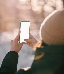 A young girl holds the mobile phone. Mockup of using smartphone outdoor. Concept of taking pictures of nature with a cellphone.