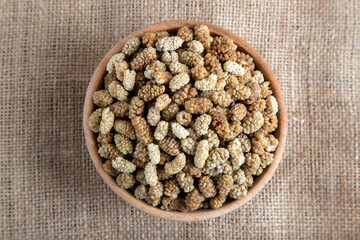 Bowl full of dried mulberry on a fabric background
