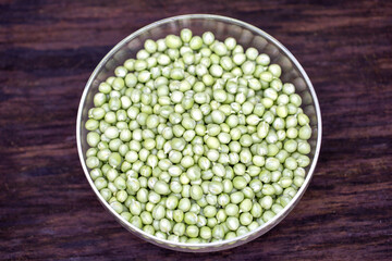 bowl of peeled baby peas, on a wooden board