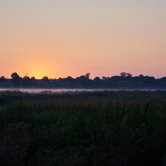 Square photo of a rural river on a background of sky during a sunset