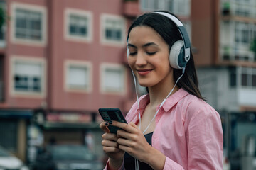 young woman with headphones and mobile phone in the city