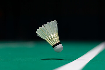 Shuttlecock floating on a green badminton court. Background, taken in low light.
