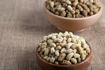 Bowl full of dried mulberry on a fabric background