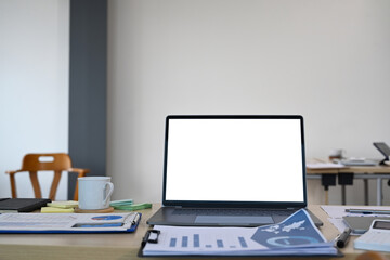 Wooden office desk with computer laptop, coffee cup and financial document