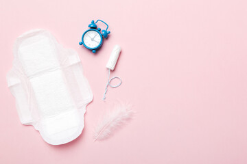Ringing alarm clock with sanitary female tampons and menstrual sanitary pads. Medical concept of woman critical days and menstruation. Female daily hygiene. Copy space - obrazy, fototapety, plakaty