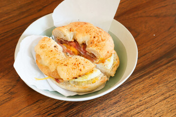 bagel with bacon ,fried egg and cheese in plate in cafe.