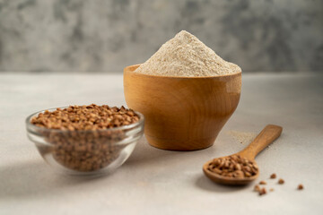 Buckwheat flour in wooden bowl, buckwheat grain, gluten free flour concept. Healthy food