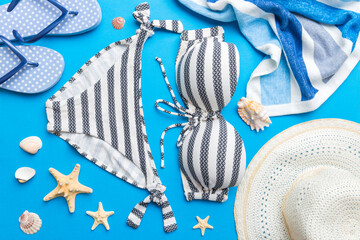 Woman swimwear and beach accessories flat lay top view on colored background Summer travel concept. bikini swimsuit, straw hat and seasheels. Copy space Top view