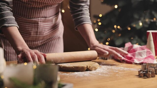 Merry Christmas, Happy New Year. Gingerbread cooking, cake or strudel baking. A young woman or mother rolls out the prepared dough with a rocking chair or wooden rolling pin for cutting out cookies