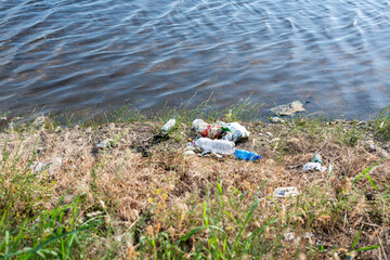 Inquinamento idrico e terrestre - Bottiglie di plastica abbandonate al ciglio di un fiume / lago 