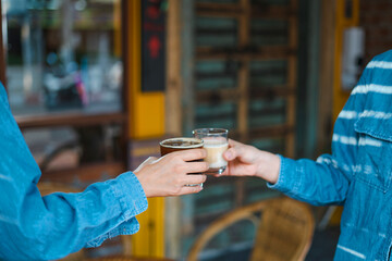 Close up of young couple hands clinking or toasting glasses of coffee talking sharing showing love...