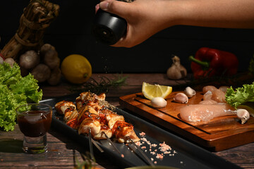 Chef is sprinkling ground pepper on grilled chicken. Barbecue, food, party concept