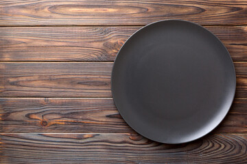 Top view of black plate on wooden background. Empty space for your design