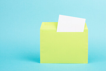 Green colored envelope with an empty with paper on a turquoise background, copy space for text, greeting card, communication and announcement concept, reminder