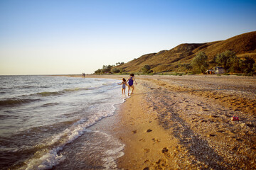 free summer vacation and happy children. Sister girls in swimsuits run and play on the seashore and mountains,