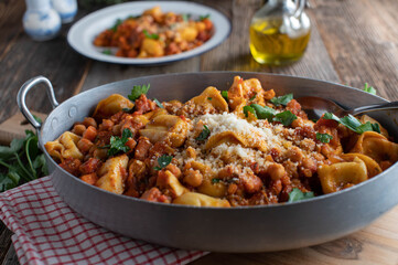 Chick pea dish with tortellini, pancetta, vegetables and tomato sauce. Served with grated parmesan cheese