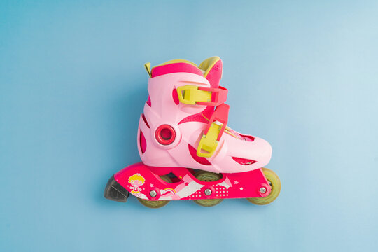 Top view of pink roller skates on blue background, top view minimal kids outdoor activity equipment 