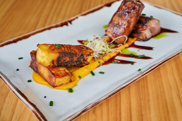 From above of plate with delicious BBQ pork and pineapple served with sauces on wooden table