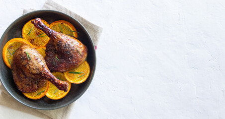 Baked duck legs with oranges and rosemary. Rustic style.