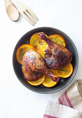 Baked duck legs with oranges and rosemary. Rustic style.