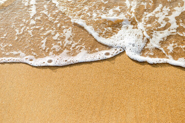 Closeup sandy beach background, fine sand with white wave, nature background, summer outdoor day light