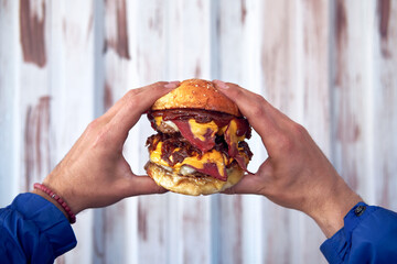 Male hand holding a delicious hamburger, burger or cheeseburger.