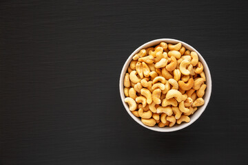 Homemade Roasted and Salted Cashews in a Bowl on a black background, top view. Flat lay, overhead,...