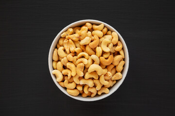Homemade Roasted and Salted Cashews in a Bowl on a black background, top view. Flat lay, overhead, from above.