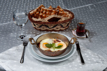 Egg omelette, bread and a cup of tea for breakfast. Omelet made in a copper pan.