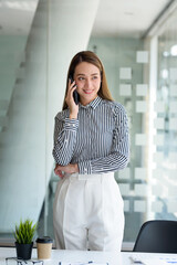 Obraz premium Happy secretary Asian business woman charming standing smiling and talking on the smartphone in the office.