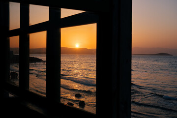 Beautiful sunset scene and sea framed with wooden window frame.