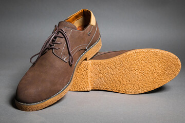 Brown suede modern shoes with laces on a grey background