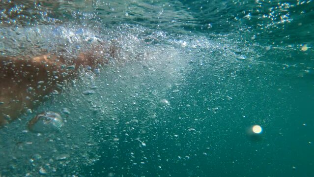 Male swimmer hand underwater making air bubbles, man drowning in sea water