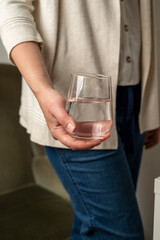 Woman holding drinking water glass in her hand. Health care concept and drinking more water. Wellbeing and health care