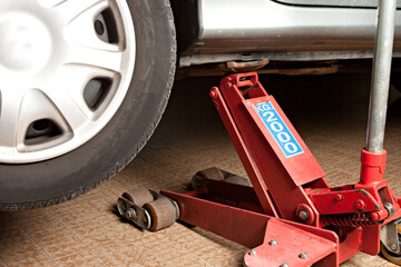 Close up of car lifted with car jack at auto mechanic workshop.