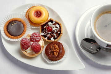 Petits Fours, kleine Kuchen auf Servierplatte, Tasse Kaffee