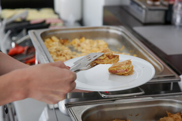 Woman taking food from a buffet line	