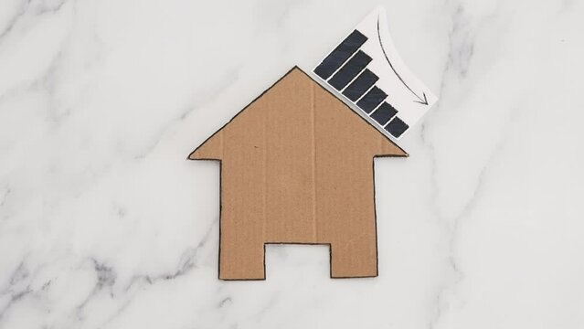 mortgages rentals and property prices decreasing, house icon made of cardboard with graph showing stats going down