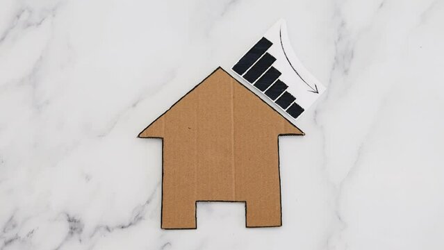 mortgages rentals and property prices decreasing, house icon made of cardboard with graph showing stats going down