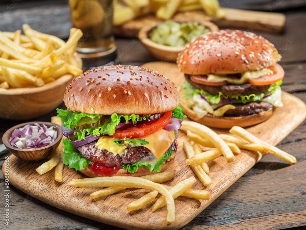 Wall mural Hamburgers and French fries on the wooden tray.