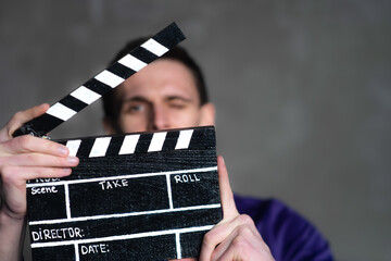 Man is holding clapperboard or clipboard in hands. Guy is directing and filming some cinema movie.